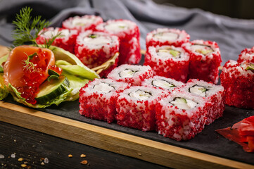 Close-up japanese sushi roll set with red flying fish caviar. Pickled ginger, spicy wasabi paste and soy sauce.