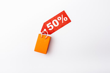 Top view of price tag with 50 percent signs and toy shopping bag on white background