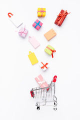 Top view of small gifts and shopping bags near cart on white background
