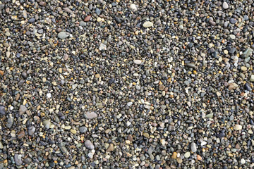 Top view of grey small wet pebble stones at sea beach. Flat lay abstract background