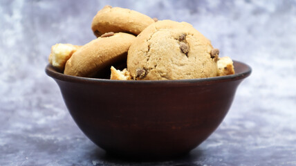 Soft freshly baked cookies with chocolate chips in a brown earthenware plate on gray marble. American traditional sweet pastry pastry, delicious homemade dessert. Culinary background.