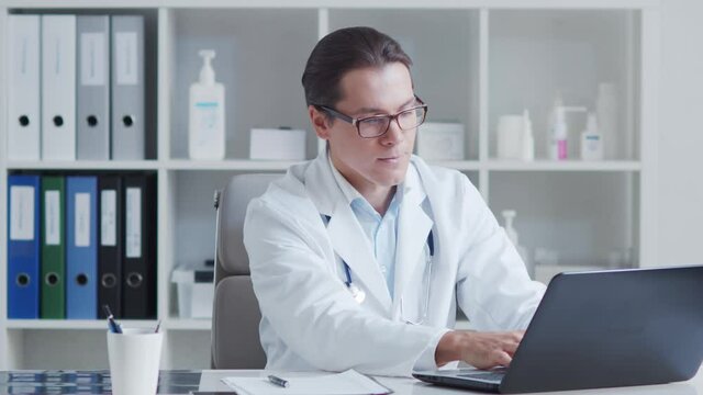 Professional medical doctor working in hospital office using computer.