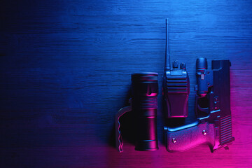 Spy secret service agent desk table concept background. Gun, radio and flashlight on the neon background with copy space.