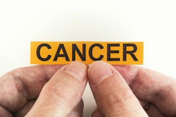 Man holding yellow piece of paper with the word Cancer
