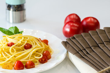 Pasta spaghetti with tomatoes and garlic served with basil leaves