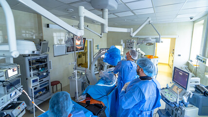 Spinal surgery. Group of surgeons in operating room with surgery equipment. Doctor is looking at...