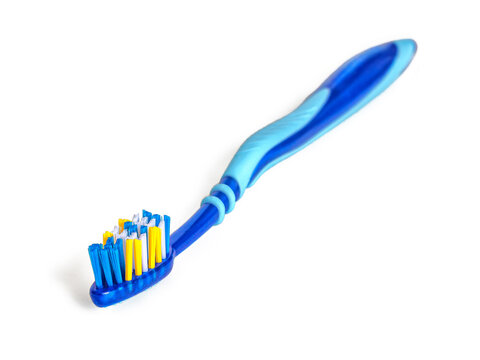 Plastic toothbrush in blue tones, with blue-white-yellow bristles, on a white