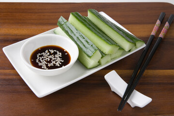 Soy Sauce With Cucumber Slices And Chopsticks On Table