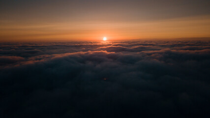 Fototapeta na wymiar Aerial morning sunrise view over the clouds in the air with ocean fog and glowing clouds