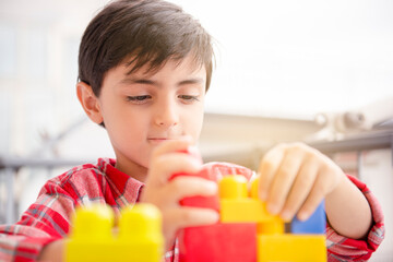 children boy playing in terrace building blocks with face mask protection