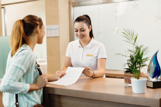 Happy receptionist talking to a customer at health spa.