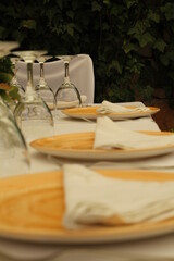 Mesa montada con platos amarillos y copas. 