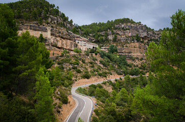 Winding road passing by the sanctuary of the Virgin of Balma built in the mountains on a cloudy day in Zorita del Maestrazgo, Castellon, Spain