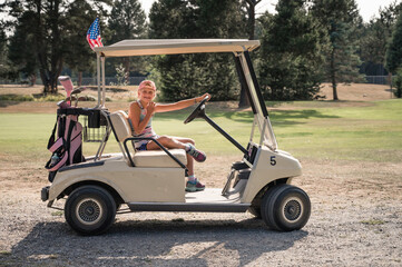 Young Girl Sitting in Golf Cart With Pink Golf Bag on Sunny Day