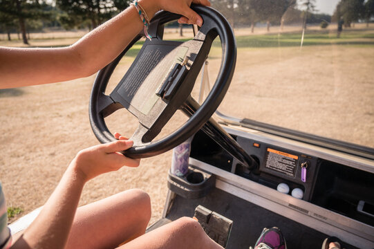 Hands Of Young Girl On The Steering Wheel Of A Golf Cart