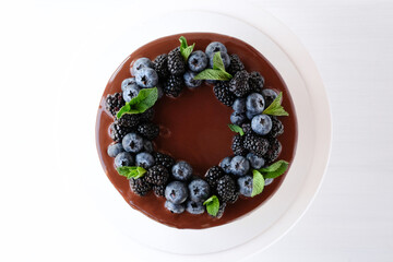 Birthday cake with chocolate, decorated with blueberries and blackberries, mint leaves on a white...