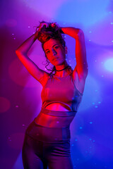 High Fashion model woman in colorful bright neon blue and purple lights posing in studio. Portrait of beautiful girl with trendy glowing make-up. Art design vivid style   