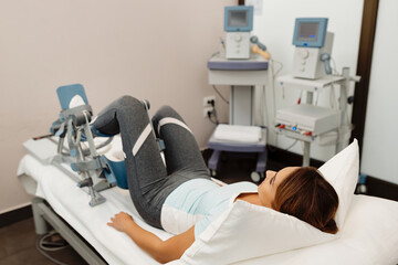 Young woman receiving leg treatment with kinetek device at health spa.