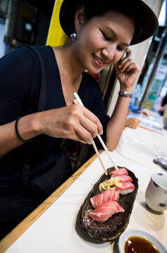 woman enjoying fresh sushi at street food market in Tokyo