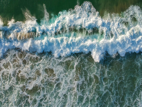 aerial view from a big wave crashing in a beach. Drone view