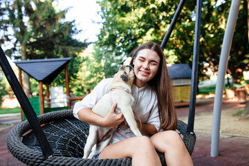 Happy dog ​​and girl. The girl is playing with a dog. Young woman walking with a pug dog in summer park. Portrait of a pug. Portrait of a beautiful pug puppy. The dog is lying on the ground.