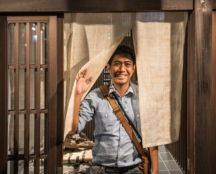 Man exiting a house in Japan through traditional Noren