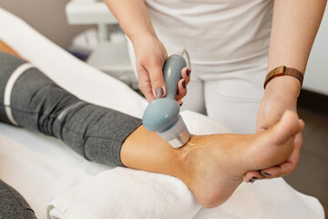 Close-up of physical therapist treating client's joint with electrotherapy.