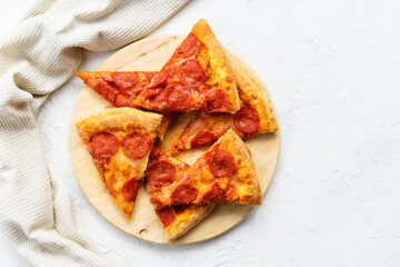 Pieces of pepperoni pizza on a wooden board. Horizontal orientation, top view, copy space.