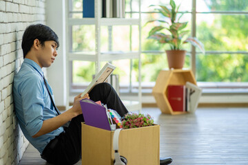 Sad disappointed Asian business man being dismissed sitting on the floor  in the office new normal