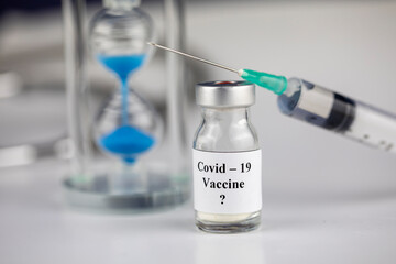 Pandemic and time Concept , Time to Vaccinate. Vaccine Bottle with Syringe for Covid-19	and hourglass
