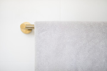 Brushed brass rain mixer shower head with running water isolated against white tiled wall in a new modern elegant bathroom lit by natural light from a nearby window modern interior house renovation 