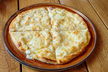 Fresh cheese pizza on a plate on the table, Italian traditional appetizer, high angle view.
