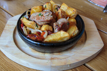 Meat in a frying pan, baked with vegetables and potatoes. Dish of Mediterranean cuisine. Restaurant shooting.