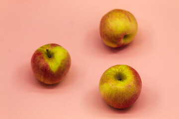On the pink background of the horizontal photo lie ripe fresh apples