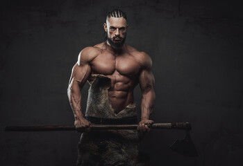 Brutal bodybuilder in fashion of ancient furios viking posing with naked torso and dreadlock in...