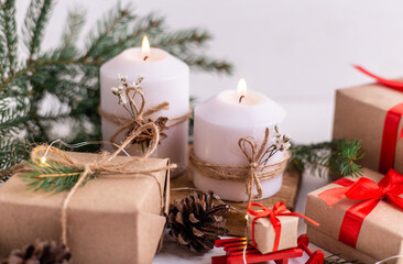 Fototapeta na wymiar Christmas burning candles and garland, fir branches, gifts and ribbon
