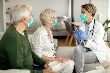 Obraz premium Female doctor talking senior couple while visiting them at home during coronavirus pandemic.