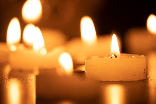 Close up of burning candles on the wooden table with blurred Christmas candles background. Selective focus.