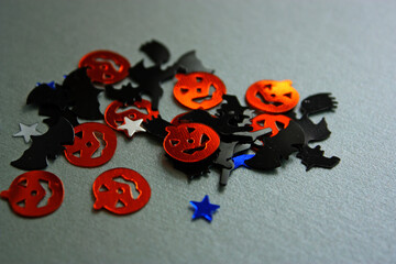 Different Halloween vivid decorations. Orange smiling pumpkins, blue and silver stars. Black witches and bats. Grey background. Autumn holiday concept. Top view, flat lay.