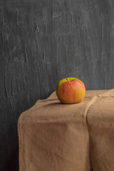 In the vertical photo a ripe small apple on a kitchen towel