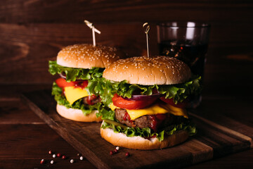 Two home made fresh tasty burgers with lettuce and cheese on wooden table.