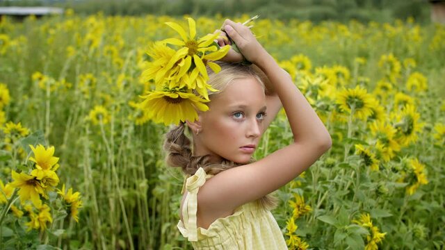 Beautiful teen girl with yellow flowers posing on blooming field. Attractive young model with sunflowers on flowering meadow in summer countryside.