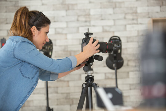 Female Photographer Setting Up Camera In Studio