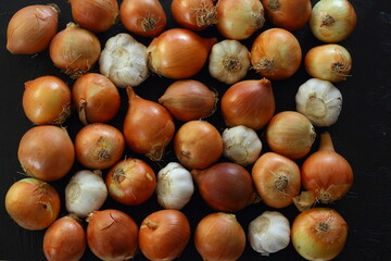 Onions and garlic over black background. Still-life of onions and falling garlic on black background