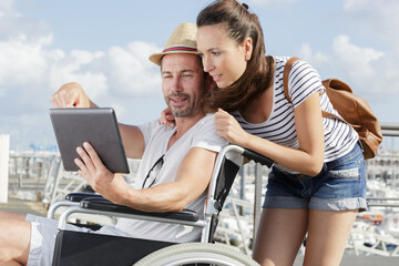 man using a tablet on his wheelchair