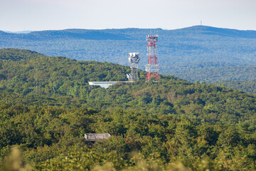 Radio cell towers in a hilly mountainous area surrounded by forest. 