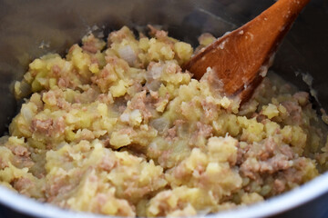 Stovies - Traditional Scottish Dish in a saucepan with a wood spoon. 