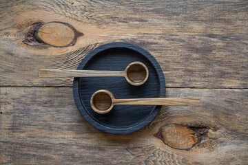 Top view two wooden spoons on black plate on wooden table, eco-friendly cutlery concept, selective focus