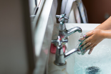 Child washing paint off hands at wash basin