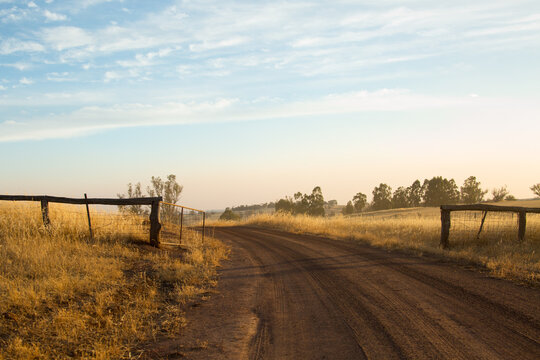 Rural landscape with gravel road leading through gateway
